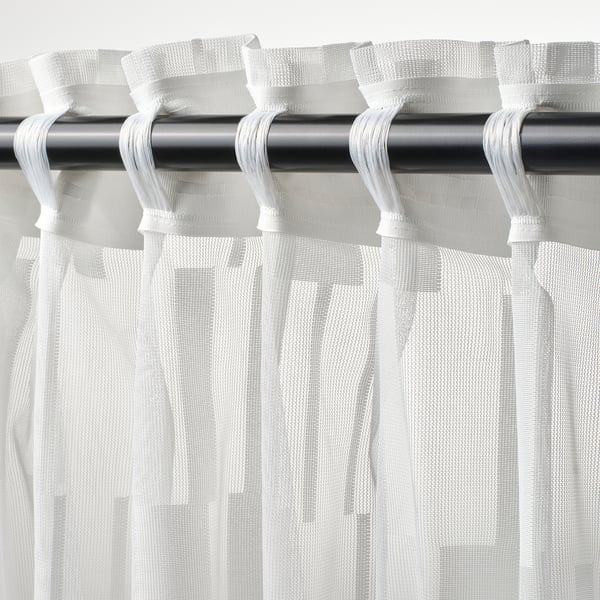 White sheered curtains with patterned transparency, hanging from rod, adjustable pleats.