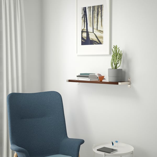 Cosy reading nook with shelf, books, cactus, armchair, print, tablet.