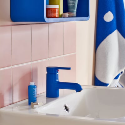 Blue tap BERGVATTNET in white sink, pink tiles, toiletries shelf, cloud shower curtain.