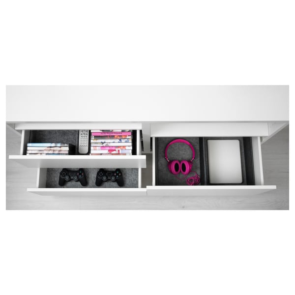 White BESTÅ storage unit with open drawers showing gaming controllers, books, and headphones.