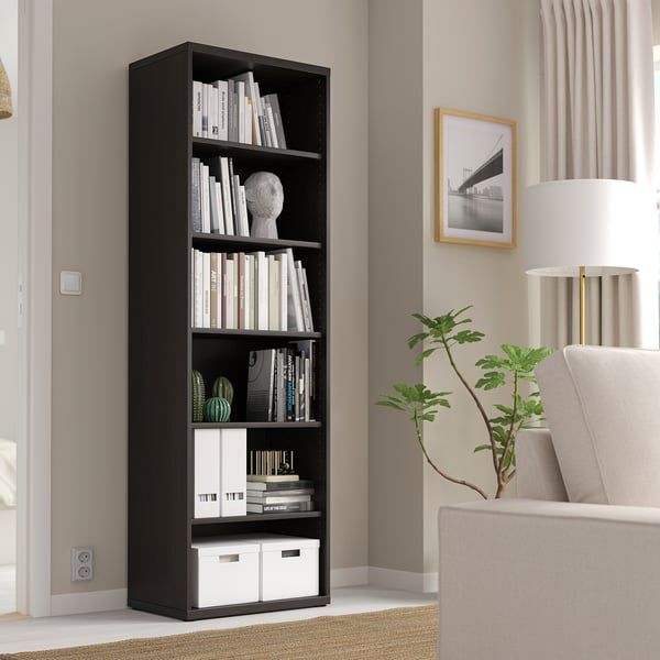 Black BESTÅ bookshelf with books and decor in modern living room.