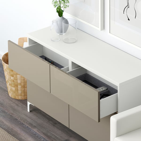 White BESTÅ storage unit with open drawer, remote control, and decorative items on top.