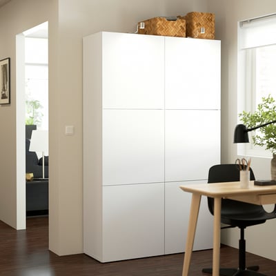 White BESTÅ cabinet in minimalist room with desk, basket.