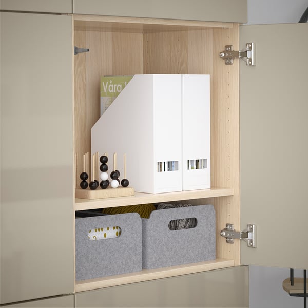White cabinet with adjustable shelves, holding magazine file, decorative spheres, and storage boxes.