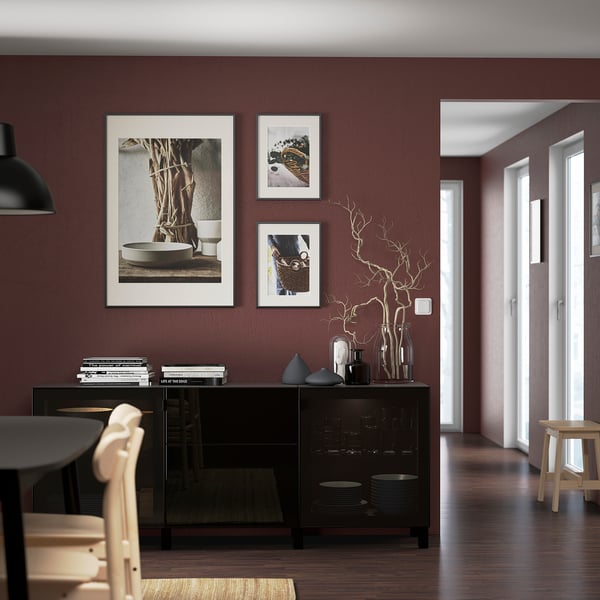 Modern dining room with maroon walls, glass-doored sideboard, and wooden chairs.