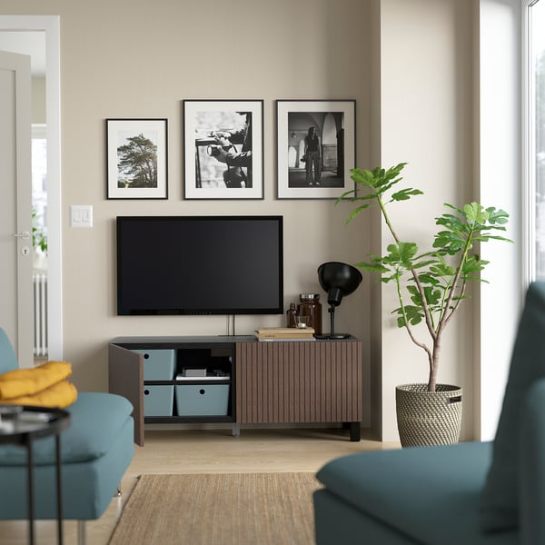 Modern living room with tv stand, adjustable shelves, and cable management. Blue bins, wall art, and plants enhance the space.