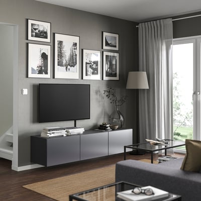 Modern living room with wall-mounted tv on grey BESTÅ unit, surrounded by black and white photos.