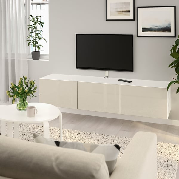 White BESTÅ tv bench with tv, paintings, plant, coffee table, and sofa.