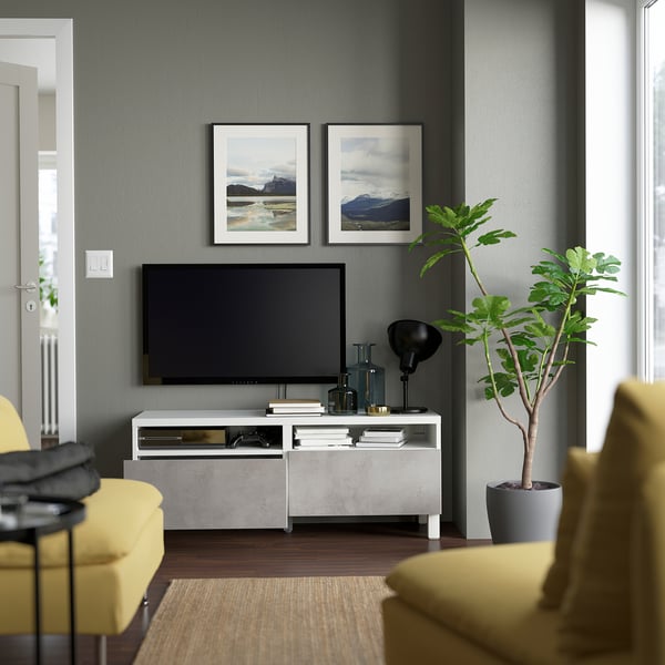 Modern living room with BESTÅ tv bench, drawers, and cable management between yellow chairs and a plant.
