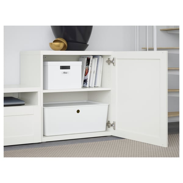 White BESTÅ storage unit with shelves and drawers. One door open, box, books, and bin visible.