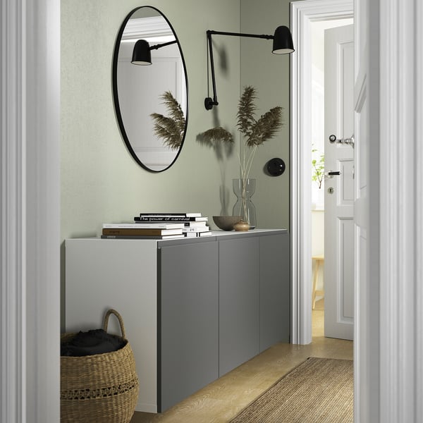 Modern hallway with BESTÅ cabinets, mirror, sconces. Basket below, vase atop, minimalist and organised.