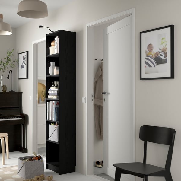 Modern living room with BILLY bookcase, chair, piano, and decor.