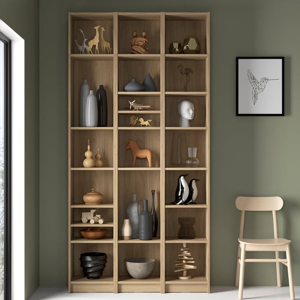 Wooden BILLY bookcase against green wall, filled with vases, sculptures, and a framed picture.