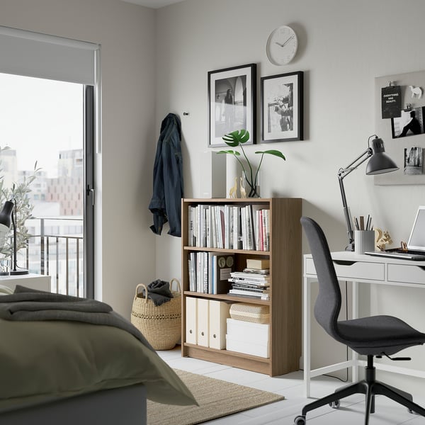 Cosy bedroom with BILLY bookcase, home office setup, green bed, city view.
