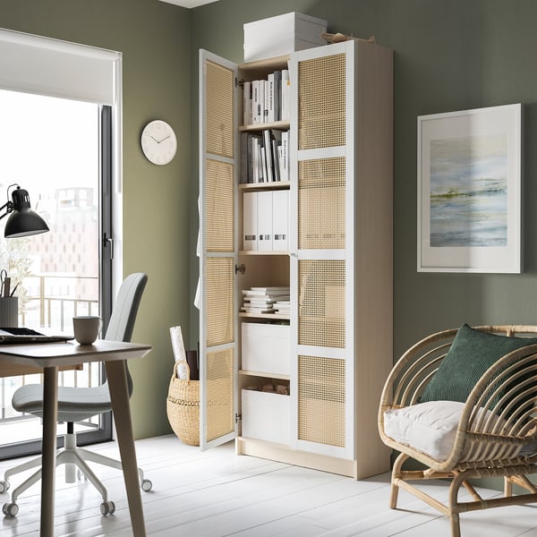 A green room with a white BILLY bookcase featuring bamboo doors displaying books and decorative items.