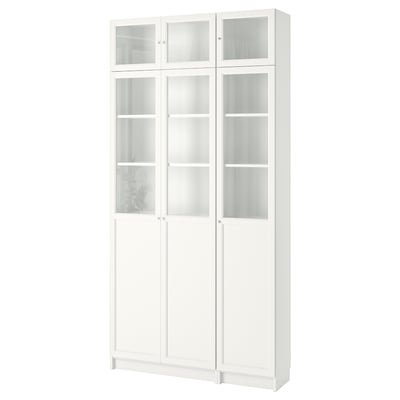 A white BILLY bookshelf with glass doors, designed in 1979. It has adjustable shelves for versatile storage.