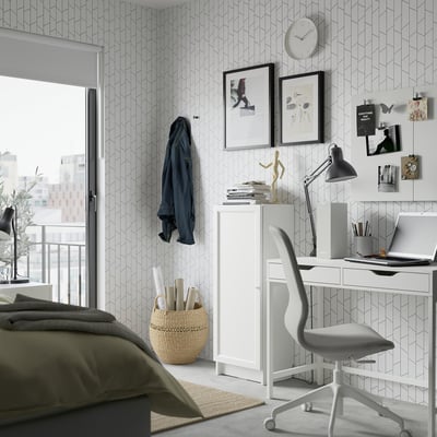 Modern bedroom a white BILLY bookcase with adjustable shelves, wooden chair, and laptop on a desk. Geometric wallpaper and a cosy rug are present.