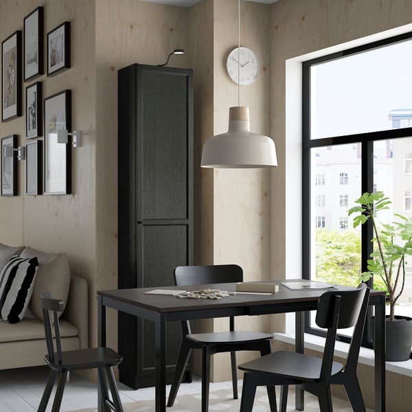 Modern dining area BILLY bookcase in black, large window, black chairs around table, beige sofa with pillows, and wall artwork.