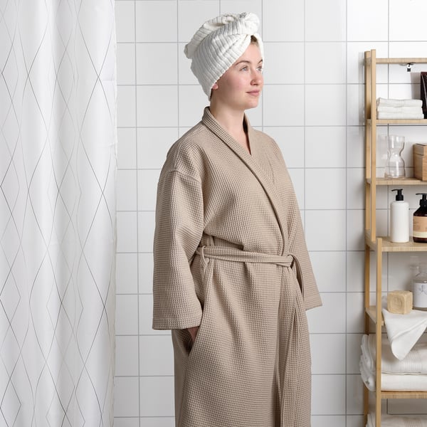 Young person modelling BJÄLVEN bathrobe with adjustable belt.