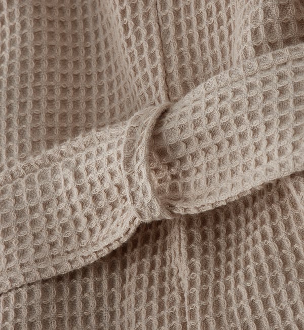 Close-up of plush, waffle-textured bathrobe, showing soft, absorbent fabric and stylish design.