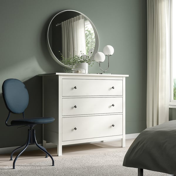 Modern bedroom with BJÖRKBERGET blue swivel chair, white dresser, round mirror, and grey bed. Green walls and light curtains.
