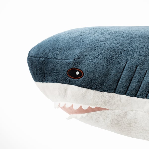 Plush blue shark toy with embroidered eyes and white teeth, made from soft polyester.