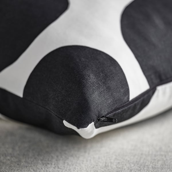 Black and white cushion with large dots, zip closure, smooth fabric.