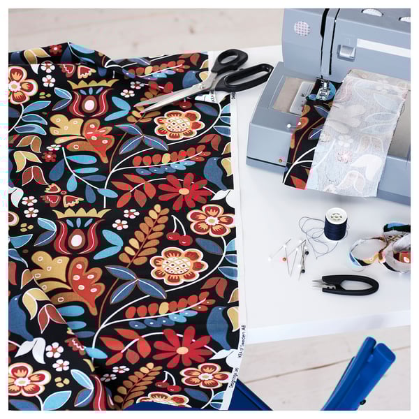 Sewing setup: patterned fabric, scissors, machine, thread, pins, tape - diy home decor.