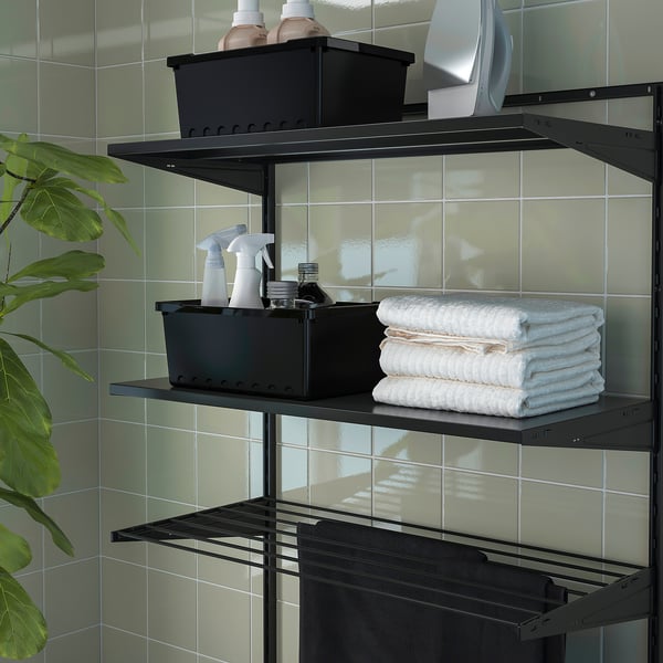 Black wall-mounted storage shelves in a bathroom, holding towels, cleaning supplies, and a black container.