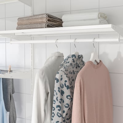 Closet with BOAXEL shelf holding folded towels and hangers with sweaters.
