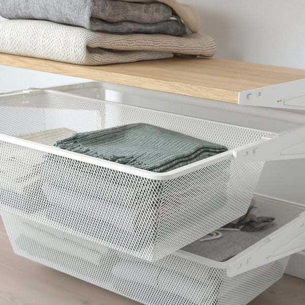White mesh drawer organiser stores green folded clothes, part of wall-mounted bedroom storage system.