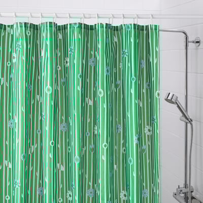 Green shower curtain BOLLBUDDLEJA with small flowers hangs in bathroom, covering entire shower area, with metallic shower head visible on right.