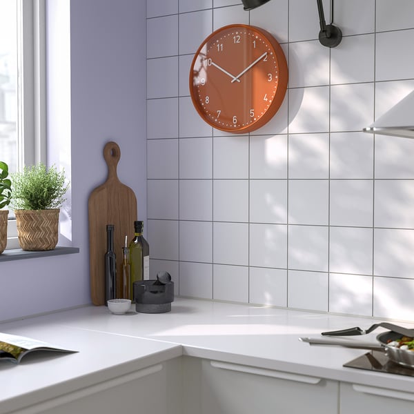 Round orange clock above kitchen counter.