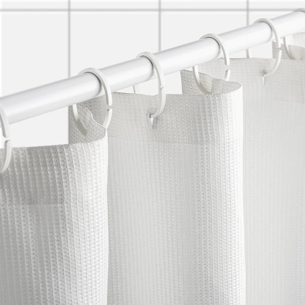 Pale grey waffle-textured shower curtain hangs from white hooks and rod. Fabric is water-repellent for durability.