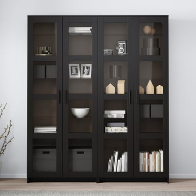 A BRIMNES black display cabinet with glass doors, showing books and decor.