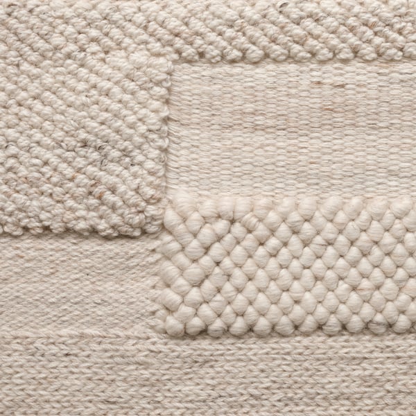 Handwoven rug with varied textures; natural tones, intricate patterns, high wool quality.