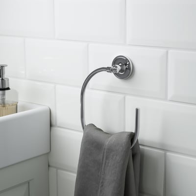 Chrome-plated towel ring on tiled wall, holding a grey towel, part of BROFJÄRDEN bathroom accessories.