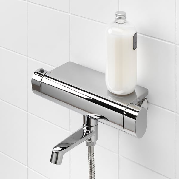 Chrome shower mixer with thermostatic control, fixed handle, and built-in shelf for a bottle. Ideal for bathroom safety.