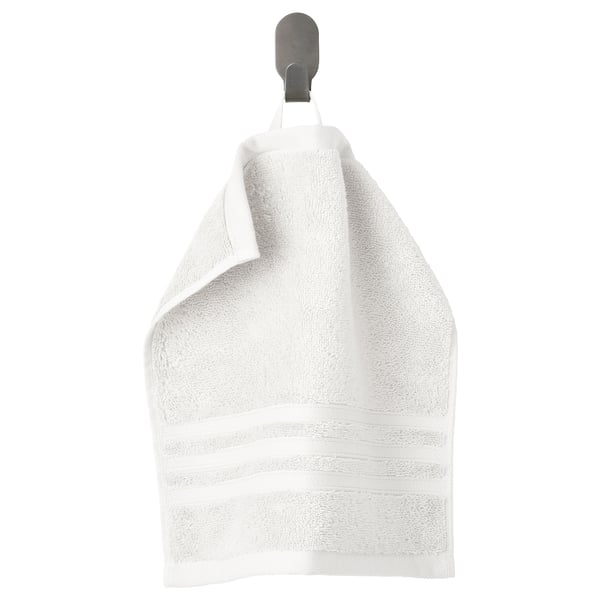 A white organic cotton towel hangs on a grey hanger, folded neatly with a woven border.