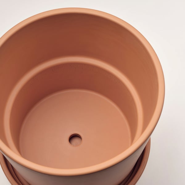 Top view of terracotta planter with drainage hole, smooth finish, and saucer.