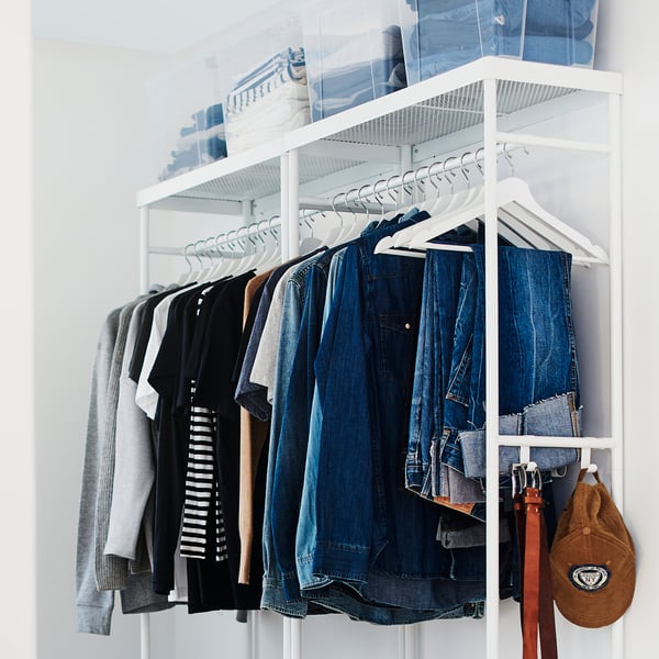 Organised closet with white hangers, jeans, t-shirts, and a backpack.