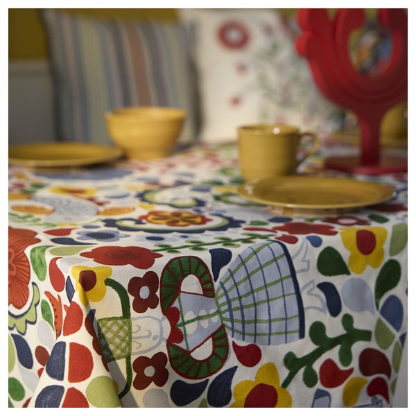 Bright, multi-colored floral tablecloth with yellow dishes.