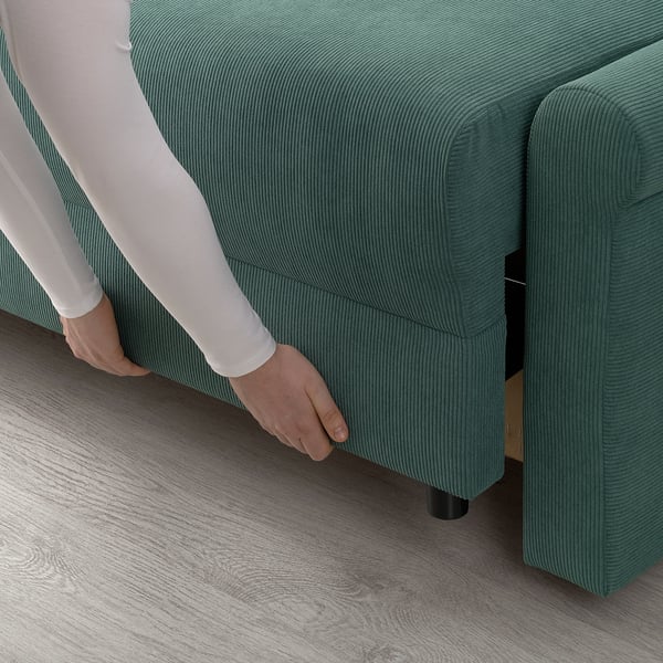 Person adjusting green sofa bed with storage, showing functionality.