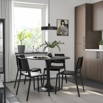 Modern dining area with black round table, chairs, and large window.