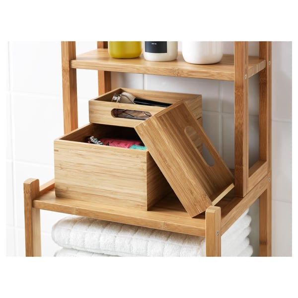 Wooden bathroom shelves with open drawers, one holding colourful items, another empty. Top shelf has three containers. Towels are below.