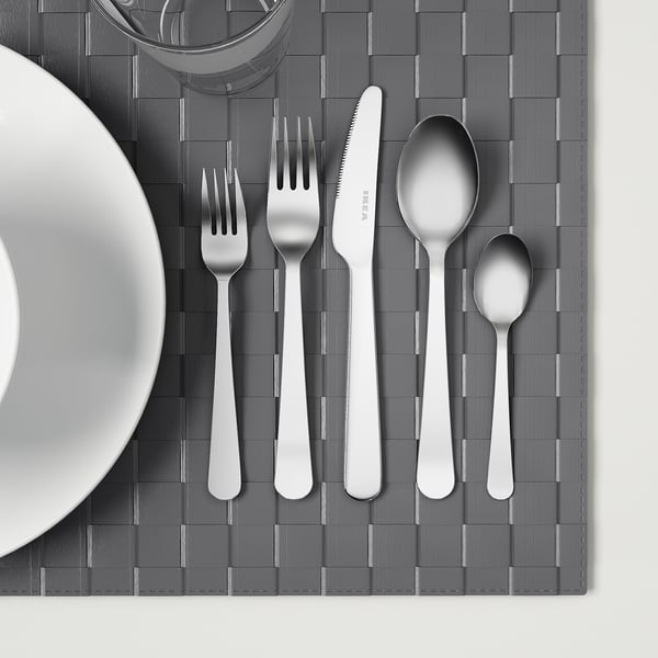 Stainless steel cutlery set on grey placemat.