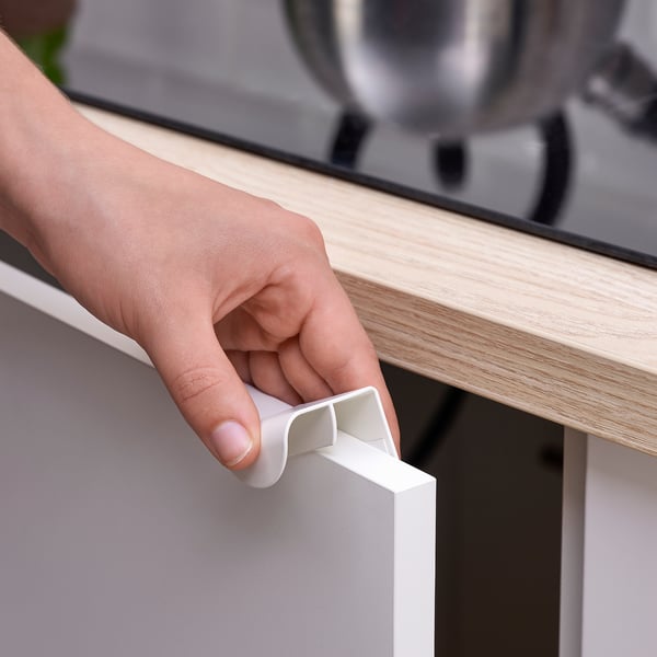 Hand clipping a rounded handle onto a cabinet, showcasing easy installation.