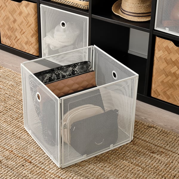 Mesh storage box with open front, revealing items inside, placed on woven rug. Perfect for organising and easily accessing items.