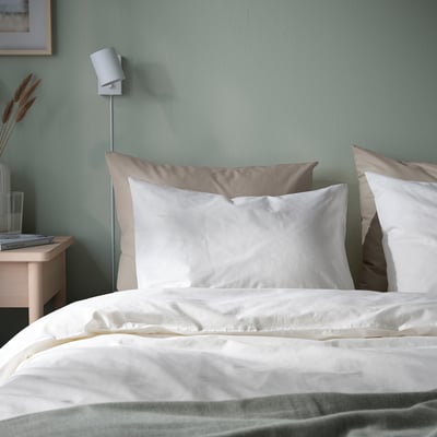 DVALA white pillowcases & bedding on mattress, wall light, small nightstand with glass, decor. Soft, natural cotton.