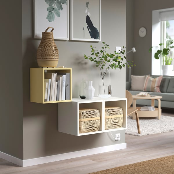 Mustard yellow EKET unit with books & decor, wall-mounted in modern living room.